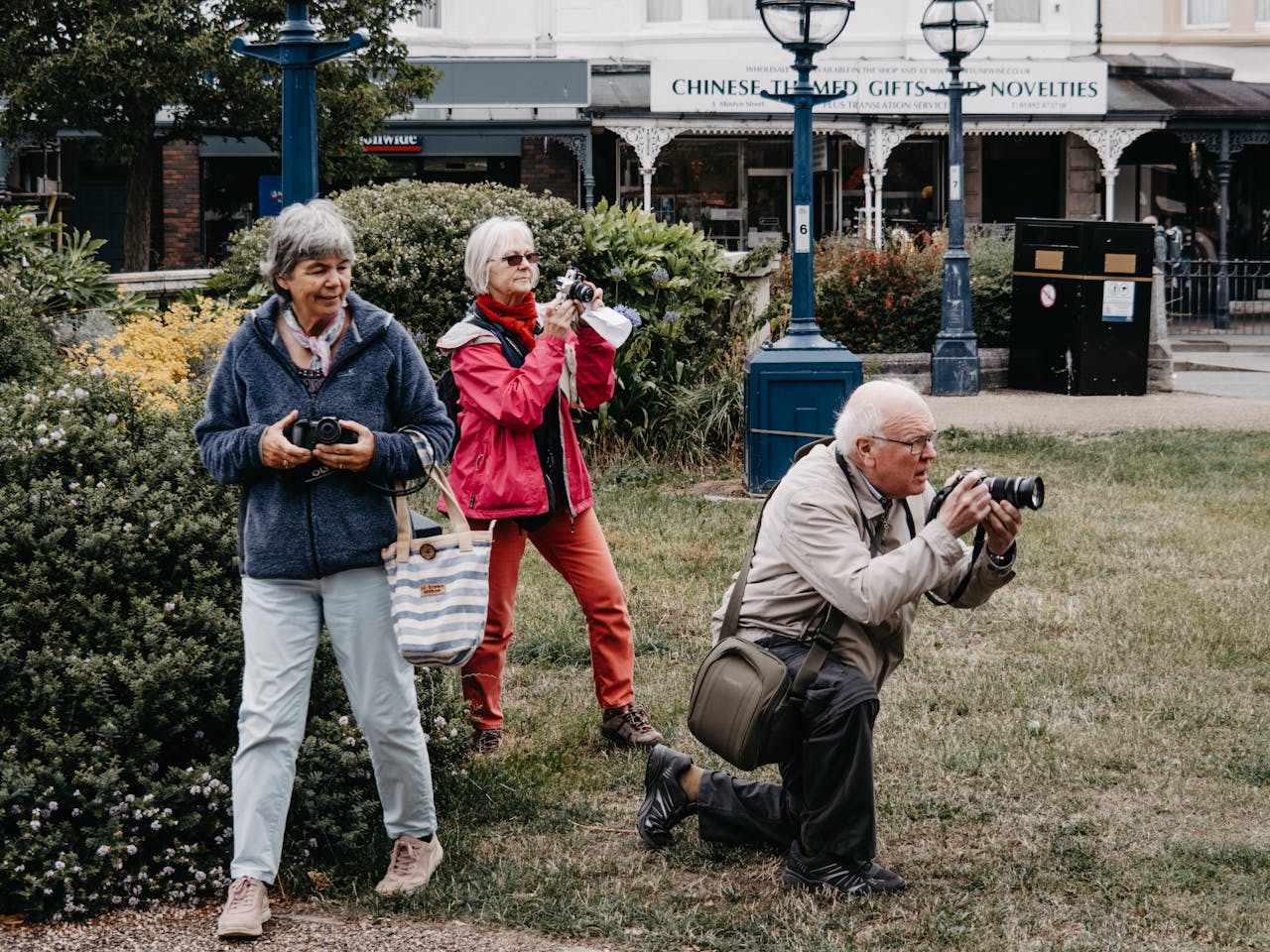 services-01 Group of senior tourists taking pictures in an urban park with cameras.